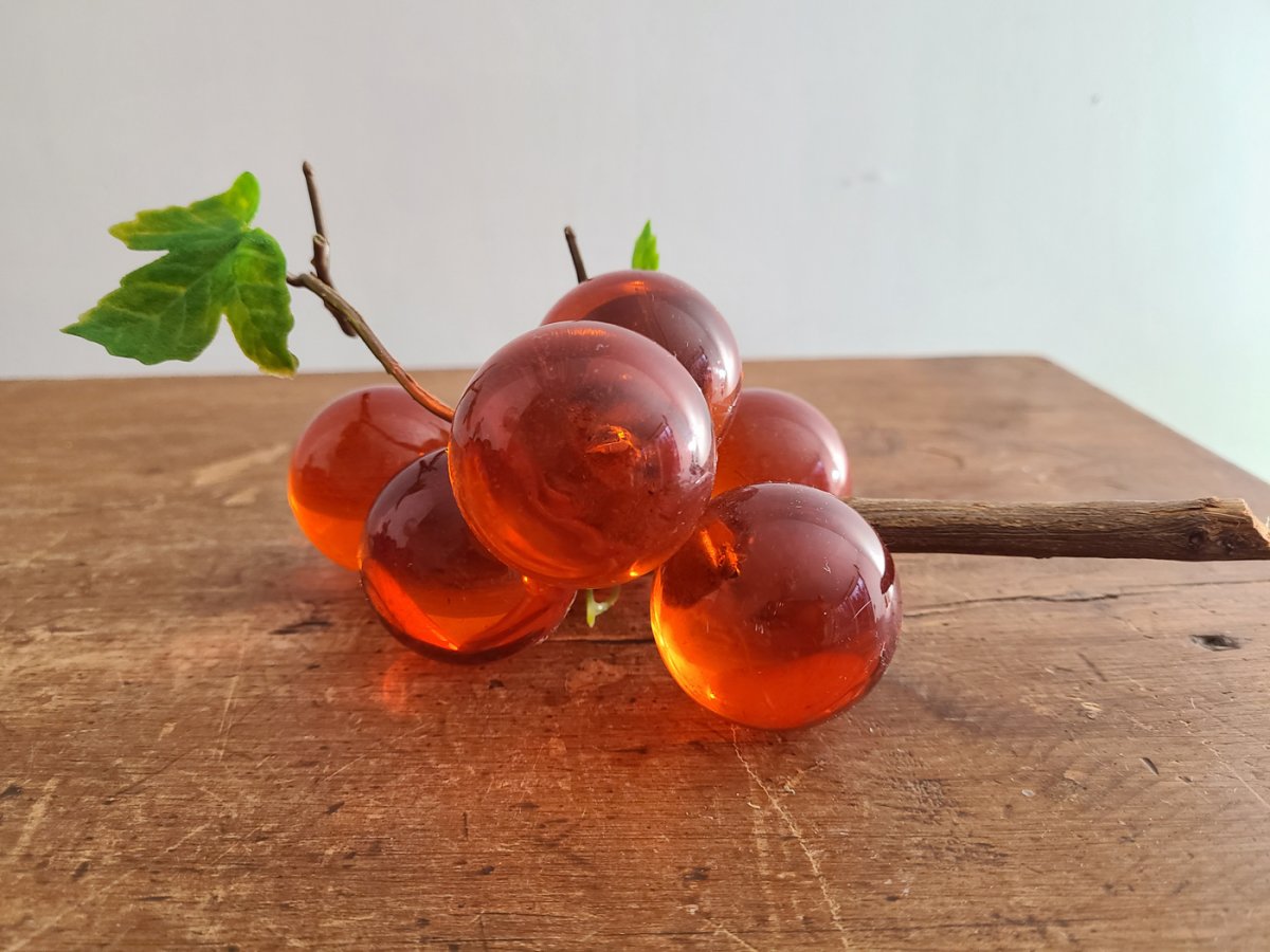 Grappe de raisin vintage en verre ambré sur branche de bois et feuilles vertes
